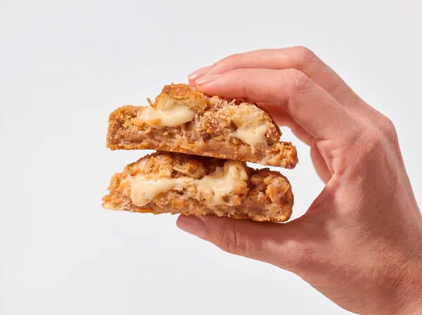 Cookie Bala Baiana partido ao meio, com coco, caramelo e chocolate branco derretido