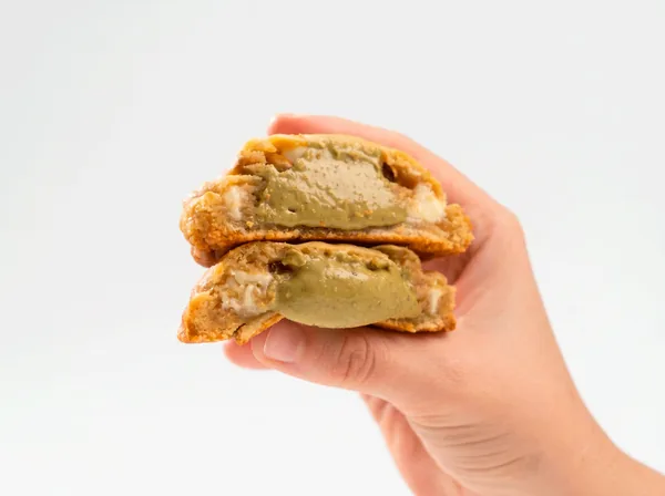 Cookie Pistachio partido ao meio, com creme de pistache verde escorrendo