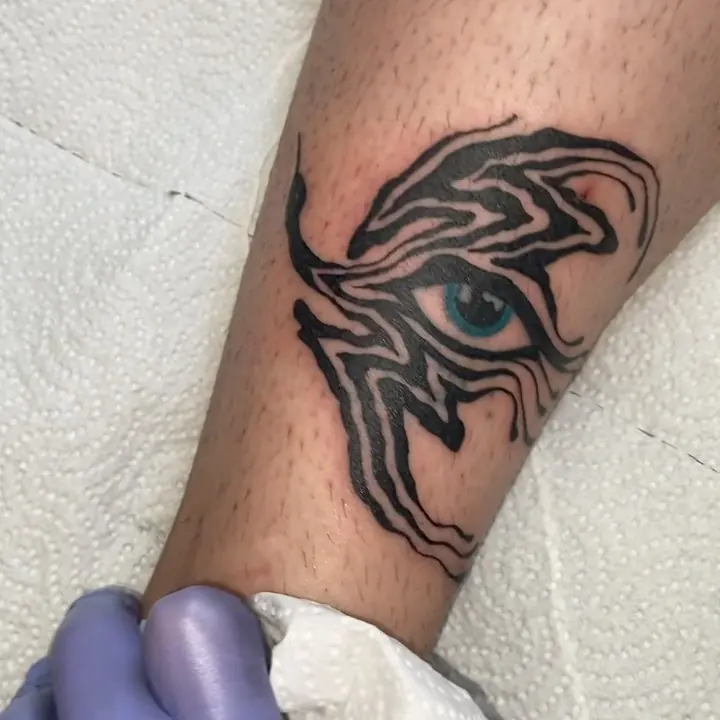 Olho com chamas em traço tribal no braço