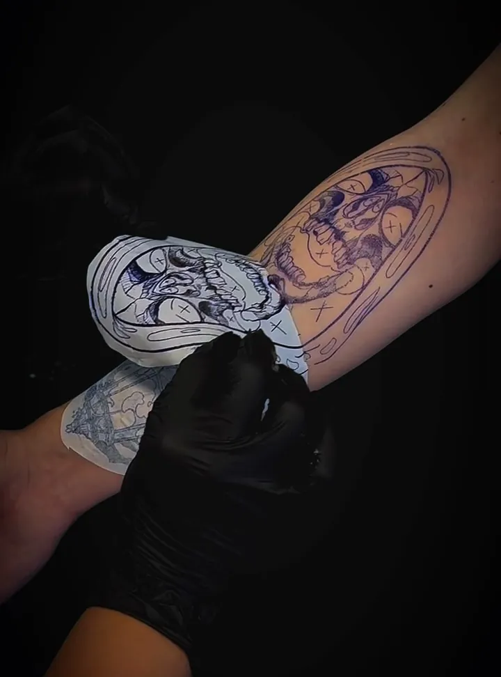 Decalque de uma arte de caveira sendo aplicado no braço antes da tatuagem