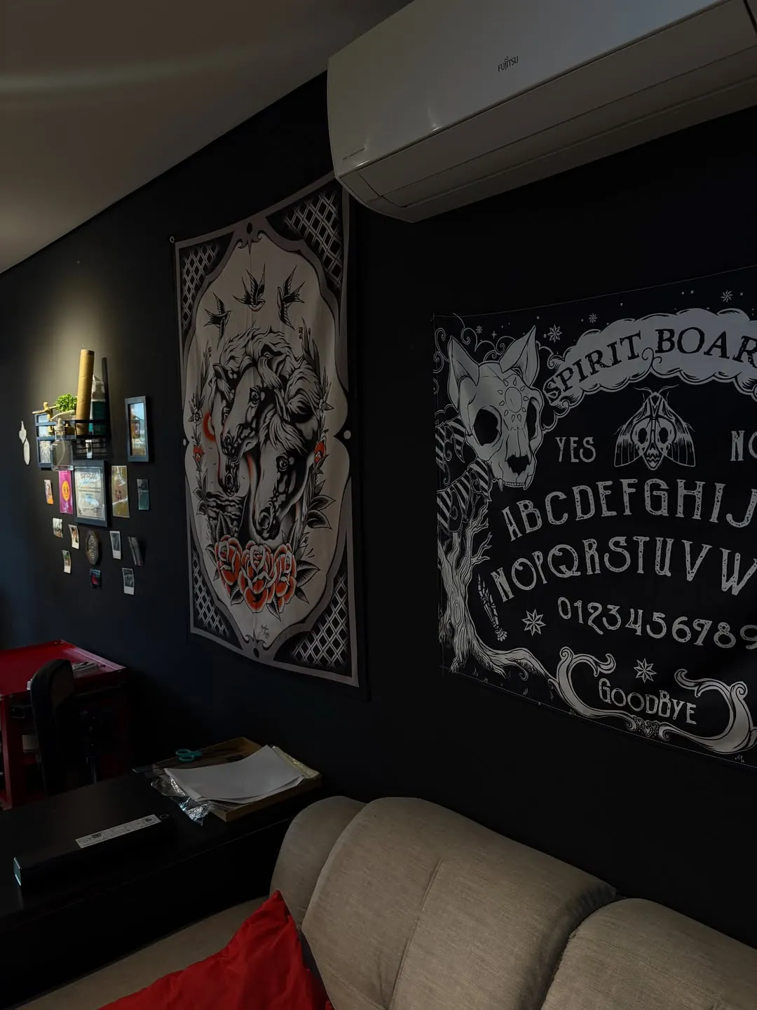 Parede preta do estúdio com tapeçaria de Ouija e quadro de caveira